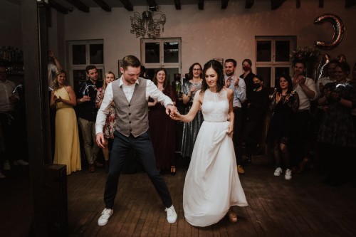 Ein Brautpaar tanzt und deren Gäste schauen zu.