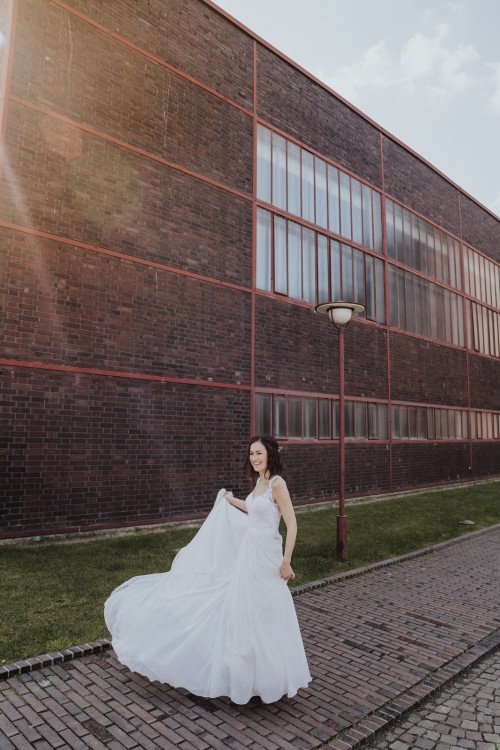 Eine Braut tanzt vor einem Gebäude.