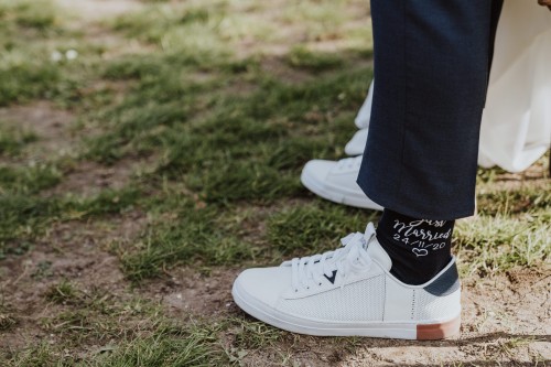 Weiße Sneakers mit schwarzen Socken mit weißer Schrift.