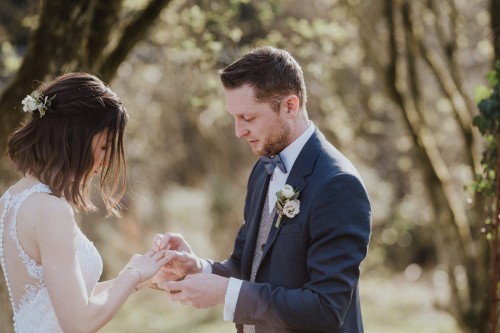 Ein Bräutigam steckt einer Braut den Ring an.
