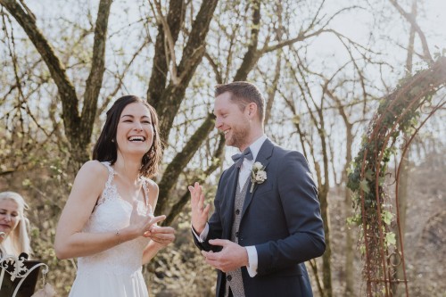 Ein Brautpaar lacht im Wald.