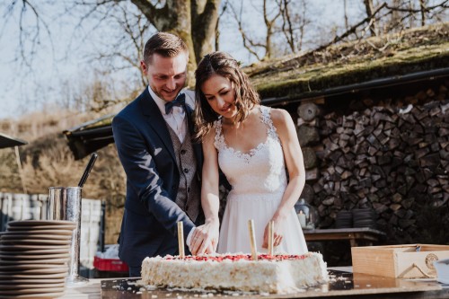 Ein Brautpaar schneidet eine Torte an.