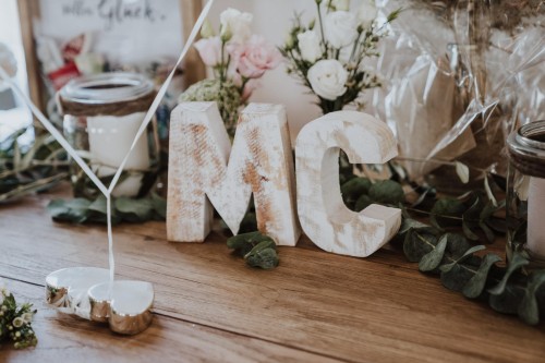 Ein Tisch mit Blumendekoration und zwei Holzbuchstaben.