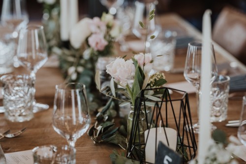 Ein Tisch mit Blumendeko und Gläsern.