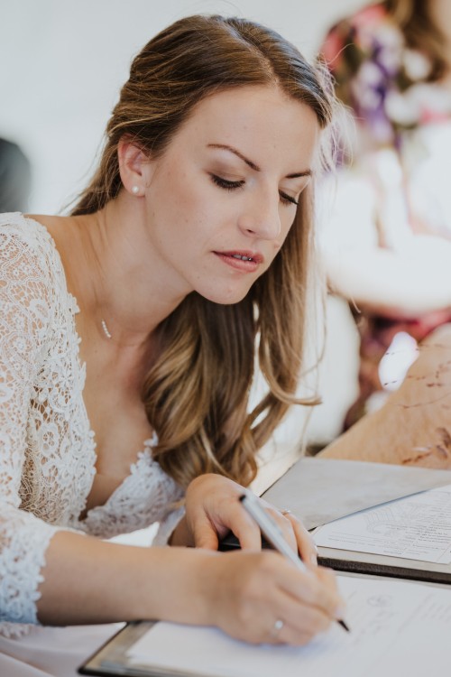 Eine Braut unterschreibt ein Dokument.