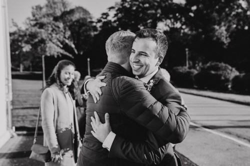 Ein schwarz-weißes Bild von einem Mann, der einen Bräutigam umarmt.