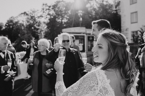 Ein Brautpaar und deren Gäste sprechen einen Toast aus.