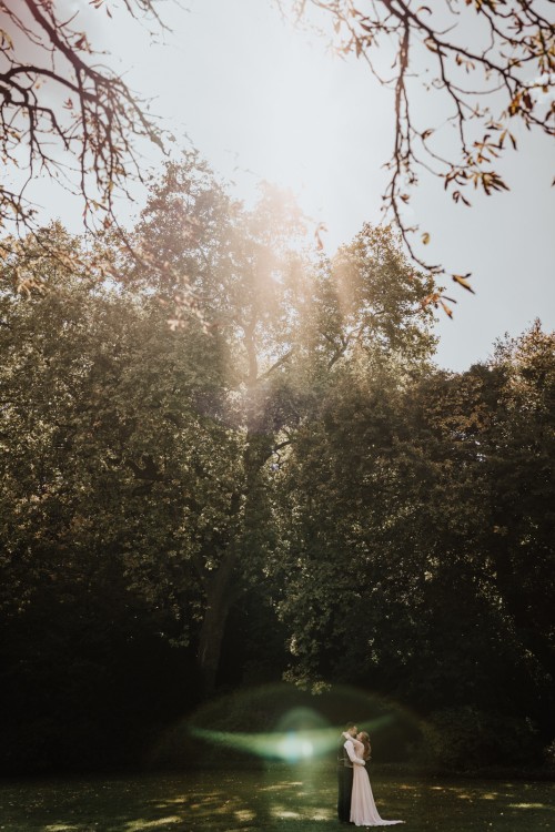 Ein Brautpaar umarmt sich vor einem Baum.