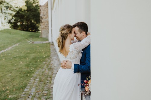Ein Brautpaar umarmt sich in einer Fensternische.