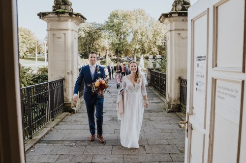 Ein Brautpaar gehen in das Standesamt rein.