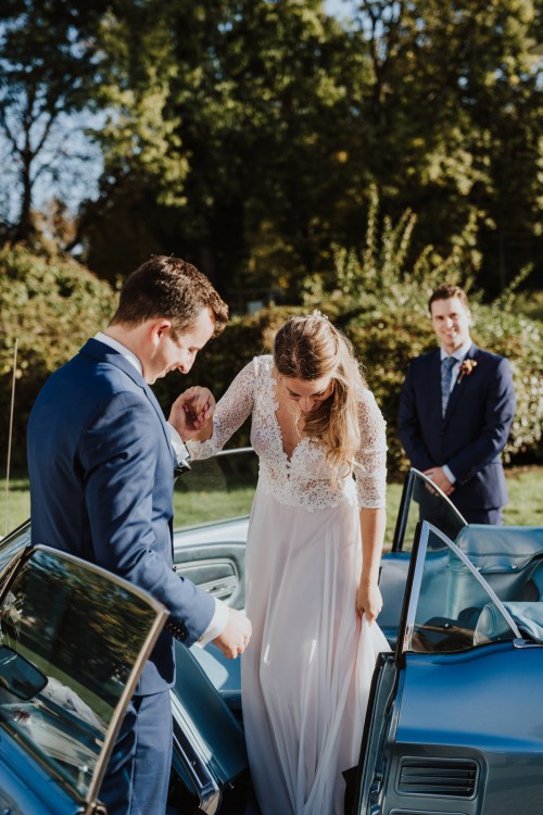 Ein Mann hilft einer Frau beim aussteigen aus einem Auto.