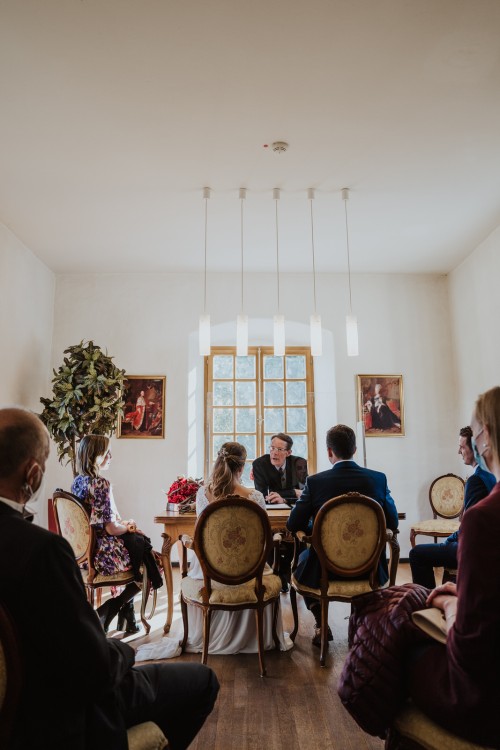 Ein Brautpaar sitzt mitten im Raum im Standesamt.