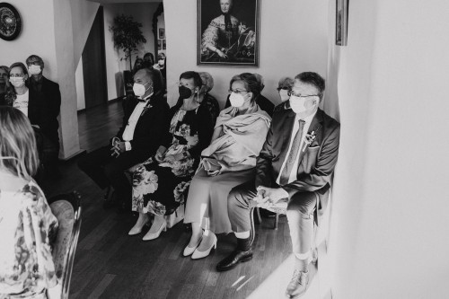 Ein schwarz-weißes Bild von einer Gruppe von Menschen die im Standesamt sitzen.