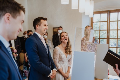 Ein Brautpaar und deren Gäste stehen im Standesamt.