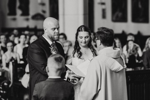 Ein Brautpaar steht vor einem Pfarrer in einer Kirche.