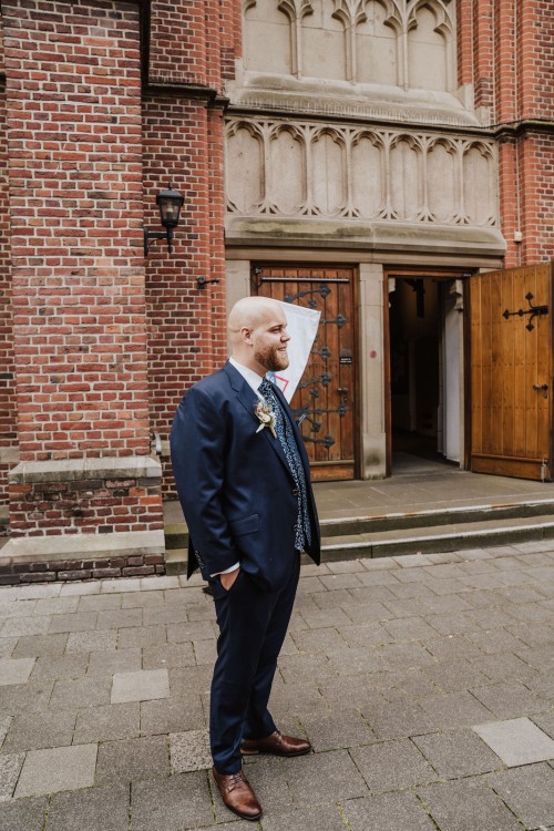 Ein Bräutigam steht vor einem Gebäude.