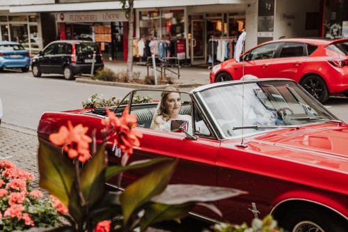 Eine Braut sitzt im roten Auto.
