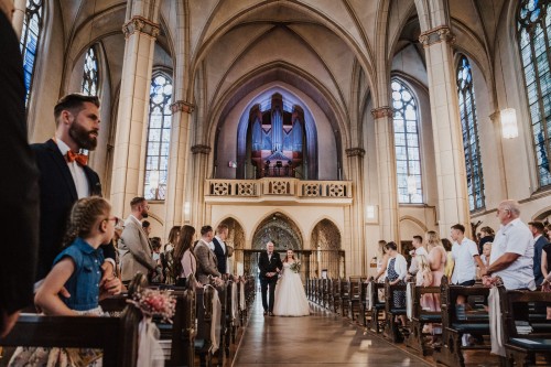 Eine Braut geht mit ihrem Papa in die Kirche.