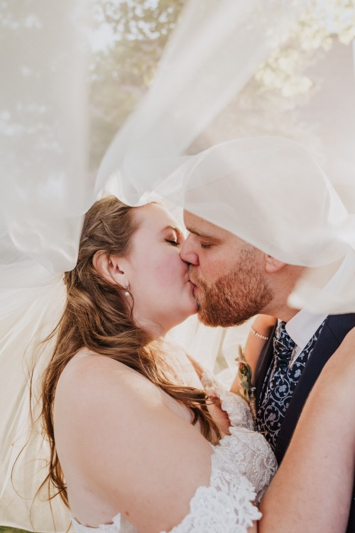 Ein Brautpaar küsst sich unter einem Schleier.