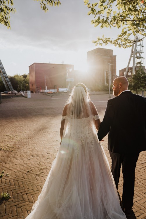 Ein Brautpaar spaziert auf einem Zechegelende beim Sonnenuntergang.