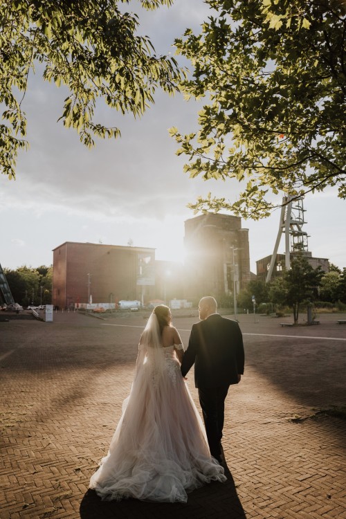 Ein Brautpaar spaziert auf einem Zechengelende.