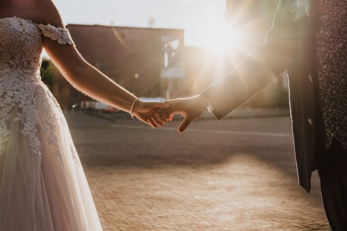 Eine Braut und ein Bräutigam halten Händchen.