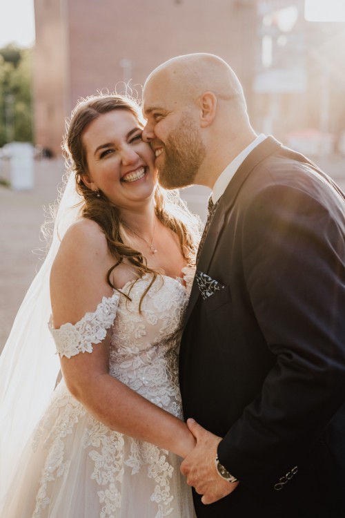 Ein Brautpaar kuscheln miteinander beim Sonnenuntergang.