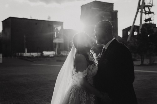 Ein Brautpaar steht vor einem Zeche Gebäude.