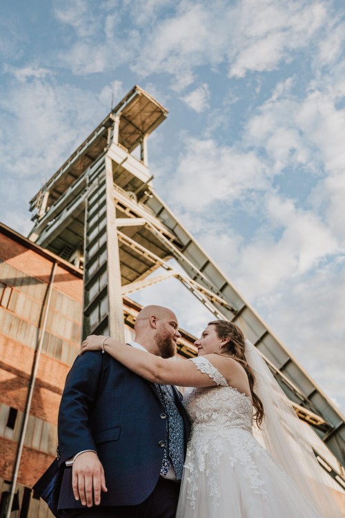 Ein Brautpaar umarmt sich vor einer Zeche.