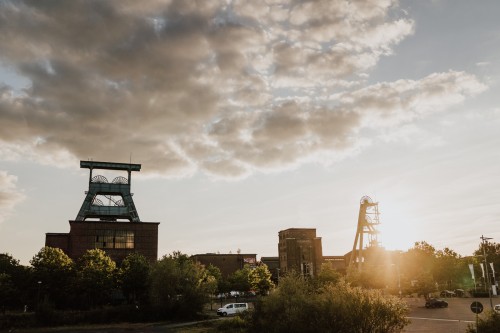 Sonnenuntergang mit einer Zeche im Hintergrund.