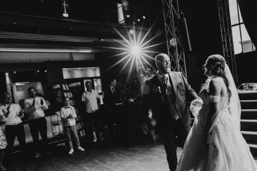 Ein Brautpaar steht mitten auf der Tanzfläche und die Gäste stehen im Hintergrund.