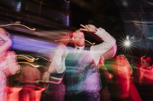 Ein Mann tanzt auf der Tanzfläche mit anderen Menschen drumherum.