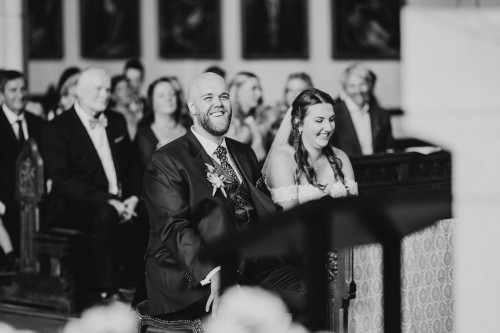 Ein Brautpaar sitzt in einer Kirche und lacht.