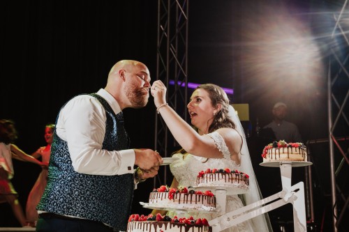 Eine Braut füttert den Bräutigam mit einer Torte.