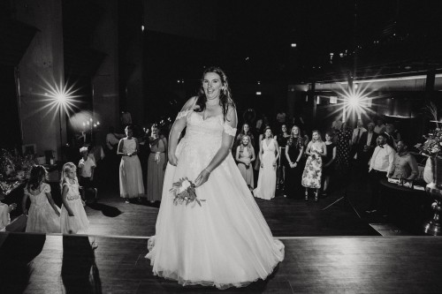 Eine Braut wirft ihren Brautstrauß zu den Frauen hinter ihr.