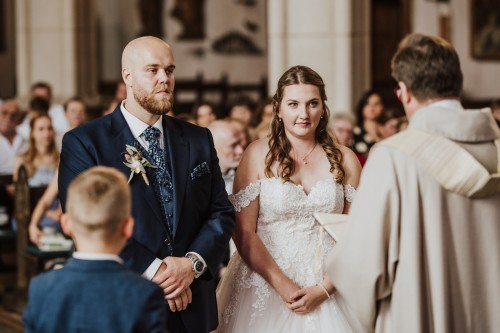 Ein Brautpaar steht in einer Kirche vor einem Pfarrer.