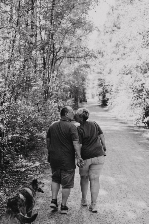 Ein Mann und eine Frau gehen mit einem Hund einen Feldweg hinunter.