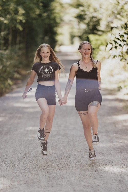 Mutter und Tochter laufen Händchenhaltend einen Feldweg hinunter.