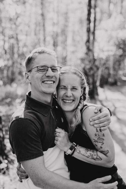 Das junge Paar umarmt sich und grinst in die Kamera.