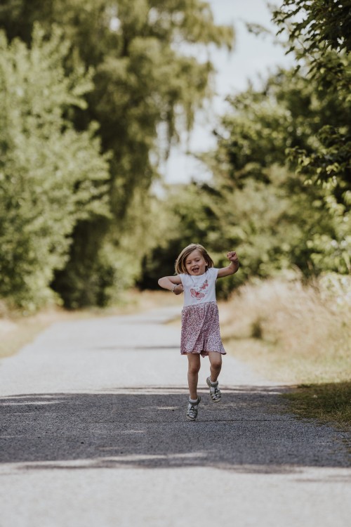 Ein kleines Mädchen rennt durch einen Wald.