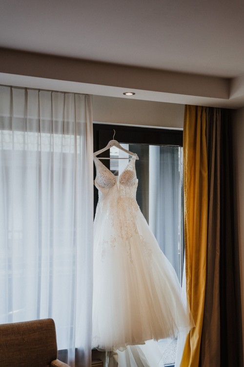 Ein Hochzeitskleid hängt vor einem Fenster.