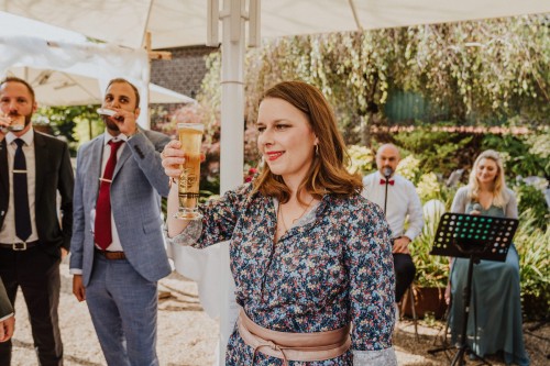 Eine Frau hält ein Bier in der Hand und bringt einen Toast aus.