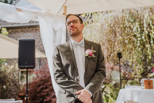 Ein Bräutigam steht unter einem Pavillon und wartet auf die Braut.