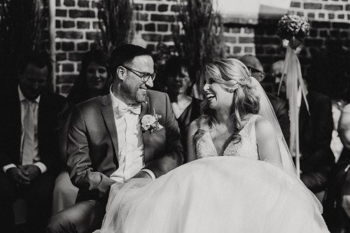 Ein schwarz-weißes Bild von einem lachenden Brautpaar.