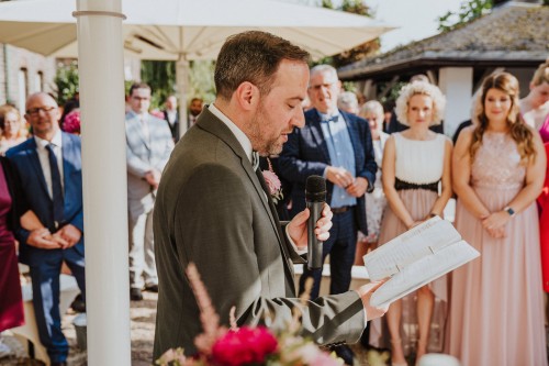 Ein Bräutigam liest ein Buch vor und die Gäste schauen zu.