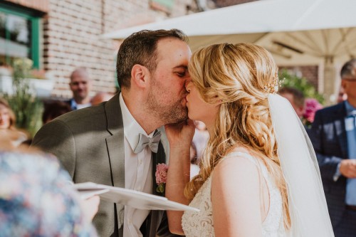 Ein Brautpaar küsst sich zwischen deren Gästen.