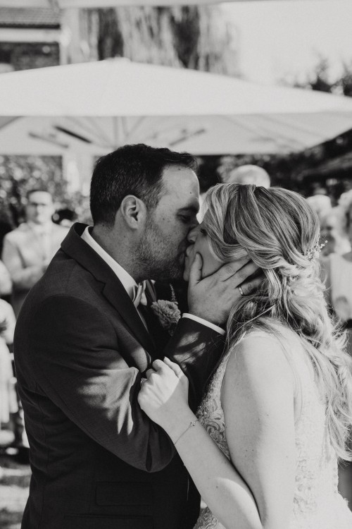Ein schwarz-weißes Bild von einem küssenden Brautpaar.
