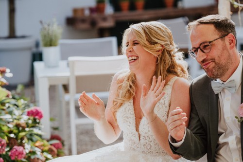 Ein Brautpaar sitzt nebeneinander und lacht herzlich.