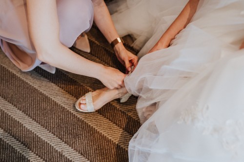 Eine Frau zieht einer Braut die Schuhe an.