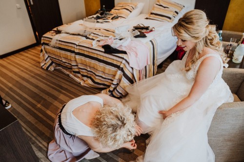 Eine Frau hilft einer Braut die Schuhe anzuziehen.
